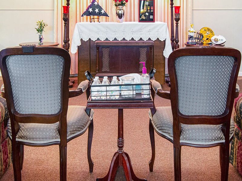 A visitation room with sofas, chairs and a memorial table
